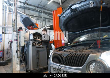 Car servicing. Technician performing a diagnostics check on a car being serviced in a service centre. Stock Photo