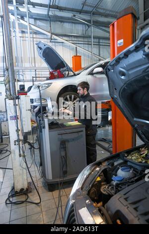 Car servicing. Technician performing a diagnostics check on a car being serviced in a service centre. Stock Photo
