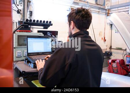 Car servicing. Technician performing an auto diagnostics check on a car being serviced in a service centre. Stock Photo