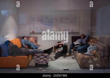 software developers sleeping on sofa in creative startup office Stock Photo