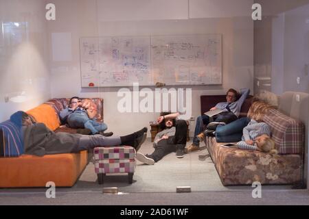 software developers sleeping on sofa in creative startup office Stock Photo