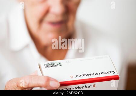 Angiotensin receptor blocker drug. 81-year-old woman handling a packet containing the angiotensin receptor blocker (ARB) drug candesartan. ARBs are us Stock Photo