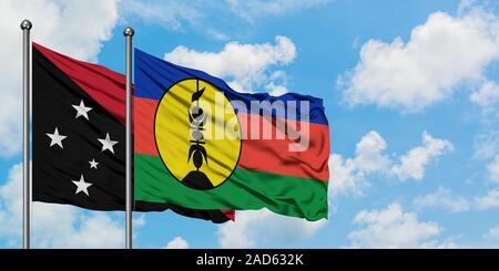 Papua New Guinea and New Caledonia flag waving in the wind against white cloudy blue sky together. Diplomacy concept, international relations. Stock Photo