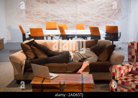 man sleeping on a sofa  in a creative office Stock Photo