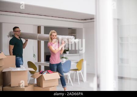 couple carrying a carpet moving in to new home Stock Photo