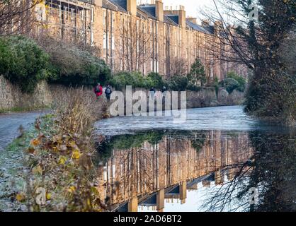 people walking on the Union Canal towpath on National Route 754 past tenement buildings, Polwarth, Edinburgh, Scotland, UK on a freezing winter day Stock Photo