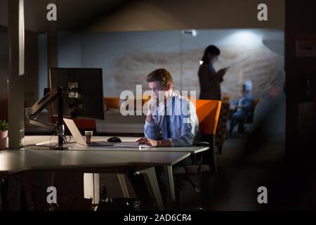 man working on computer in dark office Stock Photo