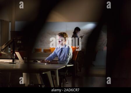 man working on computer in dark office Stock Photo