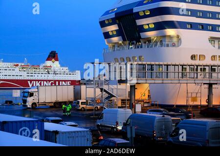 Freight truck reversing and more vehicles waiting to load onto Silja Symphony ferry on a winter evening in Helsinki, Finland. December 3, 2019. Stock Photo