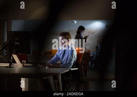 man working on computer in dark office Stock Photo