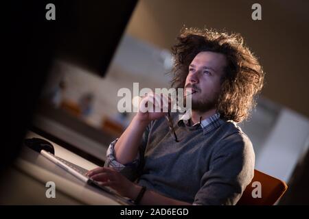 man working on computer in dark office Stock Photo
