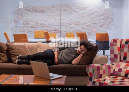 man sleeping on a sofa  in a creative office Stock Photo