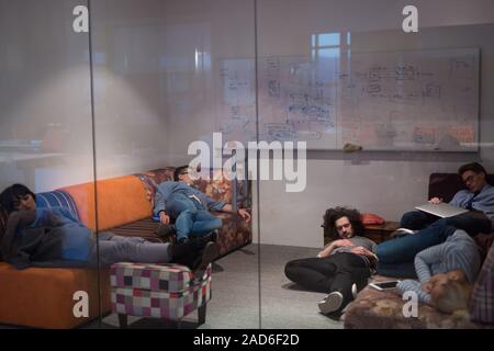 software developers sleeping on sofa in creative startup office Stock Photo