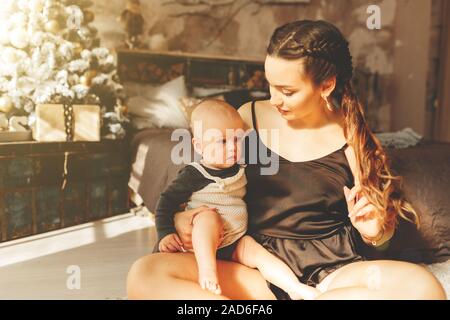 Smiling mother playing with lovely baby near Christmas tree Stock Photo
