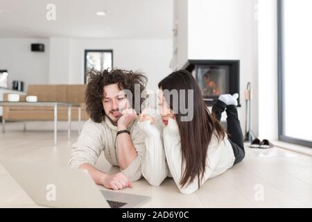 young multiethnic couple using a laptop on the floor Stock Photo