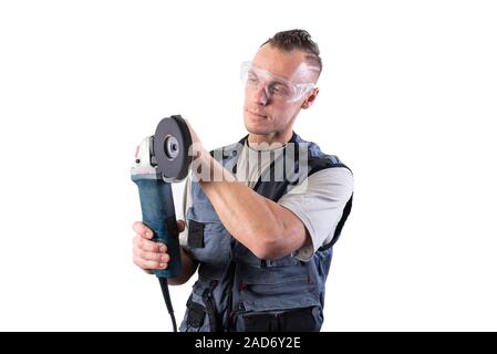 The builder in goggles, with an angle grinder in his hands. Stock Photo