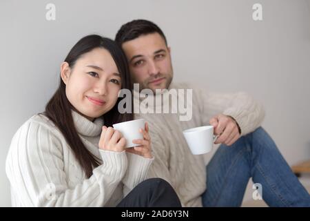 multiethnic couple enjoying morning coffee by the window Stock Photo