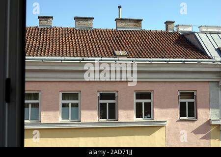 View from opened window to the top section of opposite house on bright sunny day Stock Photo
