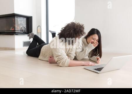 young multiethnic couple using a laptop on the floor Stock Photo