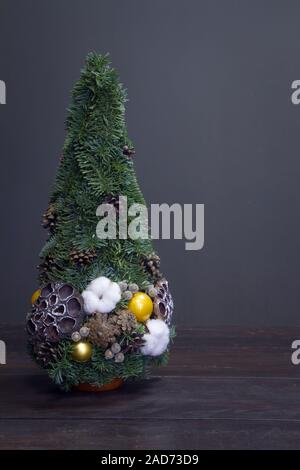 Christmas tree made of fir branches and decorated by natural materials and balls. Christmas and New Year minimalistic composition. Stock Photo