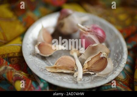 Garlic bulbs on a silver plate and vintage cloth. Stock Photo