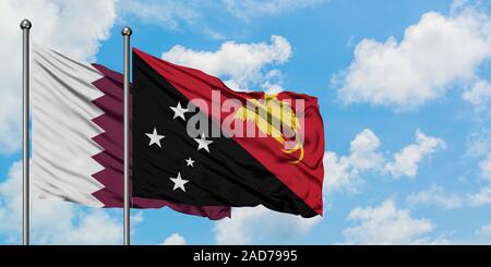 Qatar and Papua New Guinea flag waving in the wind against white cloudy blue sky together. Diplomacy concept, international relations. Stock Photo