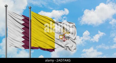 Qatar and Vatican City flag waving in the wind against white cloudy blue sky together. Diplomacy concept, international relations. Stock Photo