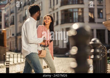 Young man and woman holding hands while crossing the street Stock Photo