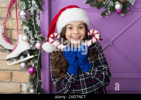 Christmas decor. Striped candy cane traditional winter holidays. Elegant happy kid in hat and gloves. Waiting for Santa Claus. Peppermint candy. Decorating ideas. Child hold christmas candy cane. Stock Photo