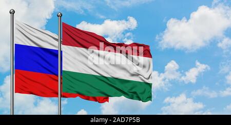 Russia and Hungary flag waving in the wind against white cloudy blue sky together. Diplomacy concept, international relations. Stock Photo