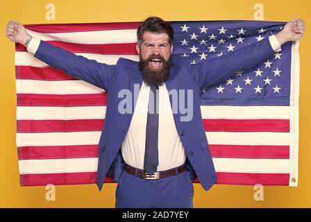 American by birth. Rebel by choice. Confident businessman handsome bearded man in formal suit hold flag USA. Successful businessman well groomed appearance. Business people. Businessman concept. Stock Photo
