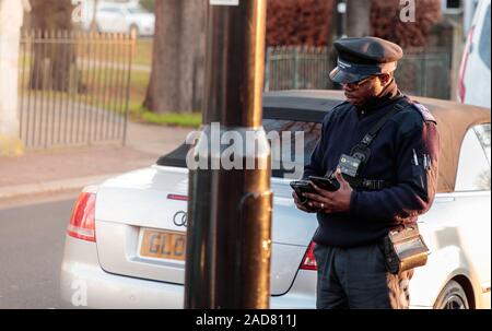 Traffic Warden writing/awarding a parking ticket (PCN) in Chiswick, London, UK Stock Photo