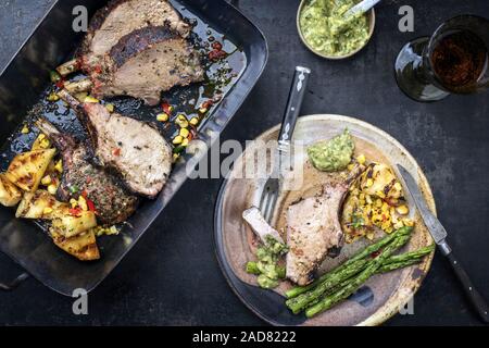 Exotically barbecue veal back racks carree roast with green asaparagus and pineapple as top view in a backing dish Stock Photo