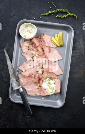 Traditional lunch meat with sliced cold cuts roast beef and remoulade as closeup on a skillet Stock Photo