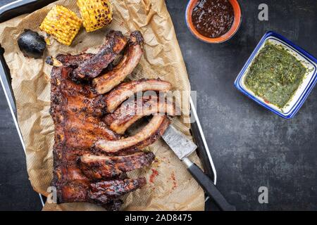 Barbecue spare ribs St Louis cut with hot honey chili marinade and chimichurri sauce as top view in a skillet Stock Photo