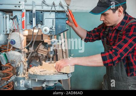 Carpenters with electric drill machine drilling wooden board Stock Photo