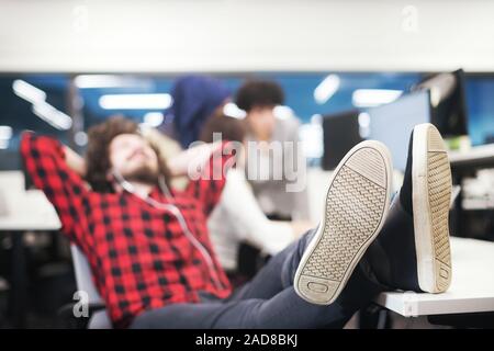 software developer resting with legs on desk Stock Photo