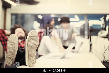 software developer resting with legs on desk Stock Photo