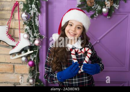 Waiting for Santa Claus. Christmas decor. Peppermint candy. Decorating ideas. Child hold christmas candy cane. Striped candy cane traditional winter holidays. Elegant happy kid in hat and gloves. Stock Photo