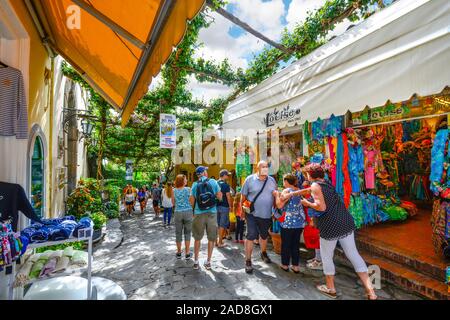 Tourists walk the narrow shaded path past cafes, shops and boutiques at the hillside village of Positano, Italy on the Amalfi Coast Stock Photo