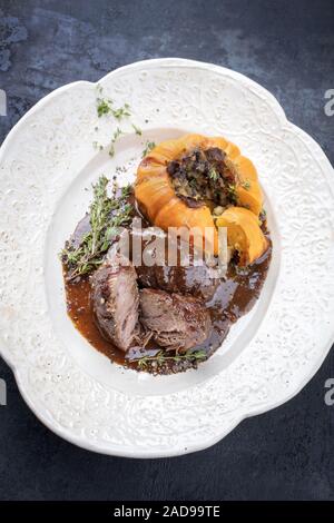 Traditional German braised pork cheeks in brown red wine sauce with mushroom and pumpkin as top view on a shabby chic design whi Stock Photo