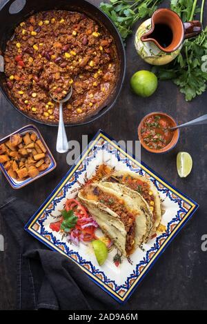 Traditional slow cooked Mexican chili con cane with tortillas as top view on a colored plate