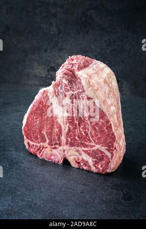 Traditional raw dry aged wagyu porterhouse steak as closeup on an old rustic board Stock Photo