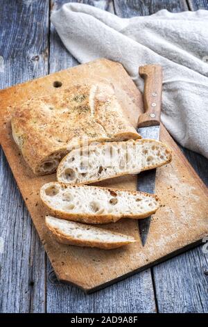 Traditional Italian ciabatta bread with herbs as closeup on a cutting board Stock Photo