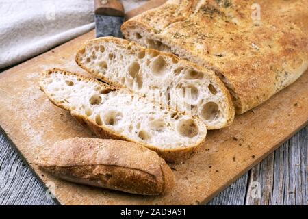 Traditional Italian ciabatta bread with herbs as closeup on a cutting board Stock Photo