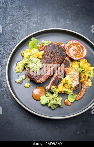 Traditional exotically blackened Cajun style tuna fish fillet with mango avocado salad Stock Photo