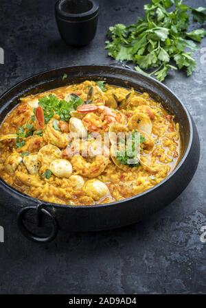 Traditional Portuguese arroz caldoso con almejas with shrimps and calm as top view in a cast-iron pot Stock Photo