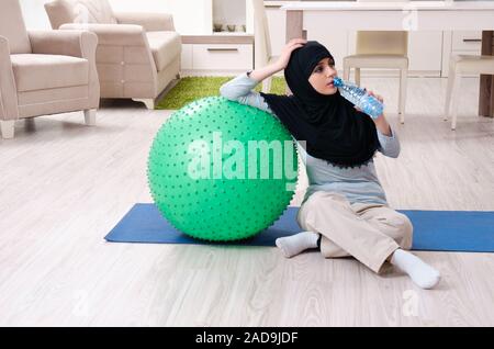 Young woman in hijab doing exercises at home Stock Photo