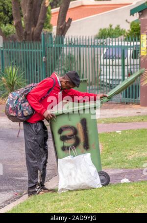 Alberton, South Africa - unidentified elderly black man digs in garbage bins on a public street image in vertical format Stock Photo