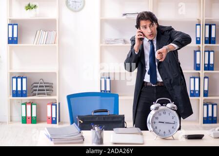 Young male employee in the office in time management concept Stock Photo